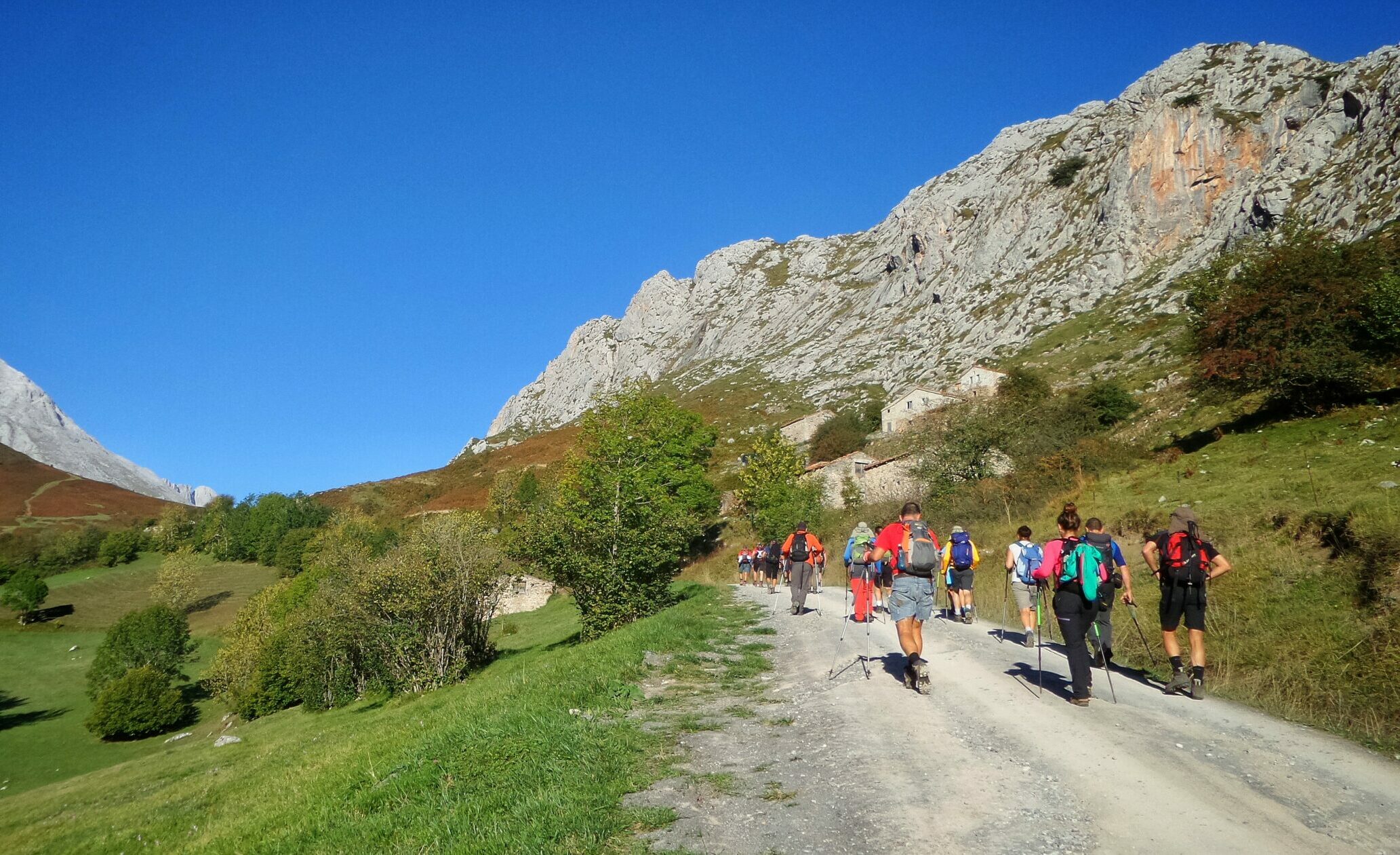 Hikers walking through a pathway surrounded by hills covered in greenery under the sunlight